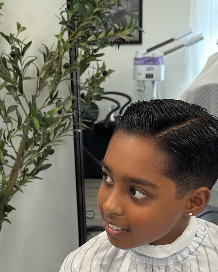 Young boy in the Signore pinstripe cape with a sharp side part and taper